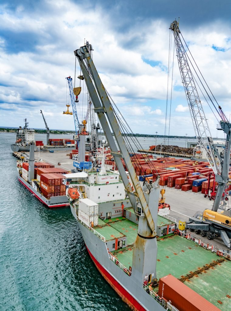 A massive cargo ship docked beside a large bridge